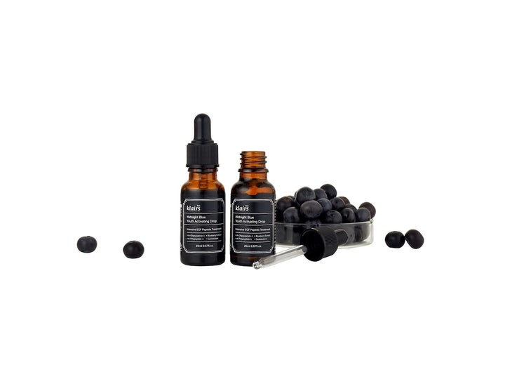 Klairs Midnight Blue Youth Activating Drop 20 ml anti-age ansiktsserum i brune glassflasker omgitt av friske blåbær.