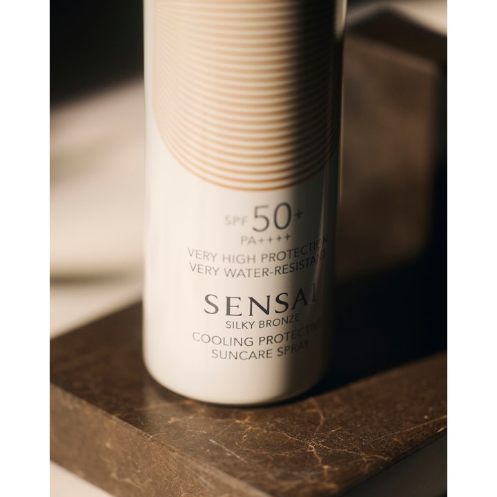 Sensai Silky Bronze Cooling Protective Suncare Spray SPF50 150 ml hvit sprayflaske med bronsemønster på mørk marmor
