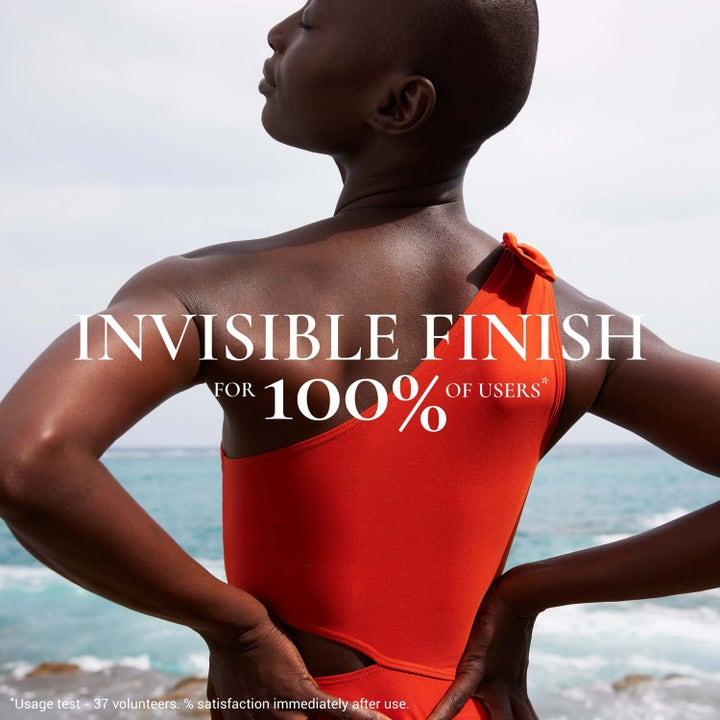 Nuxe Sun Mist Fresh SPF 30 150 ml solkrem til kropp gir usynlig finish vist på kvinne i orange badedrakt ved havet.