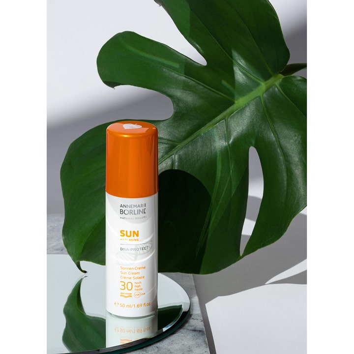 Annemarie Börlind Sun DNA Protect SPF 30 50 ml solbeskyttelse i hvit flaske med oransje kork foran et grønt blad