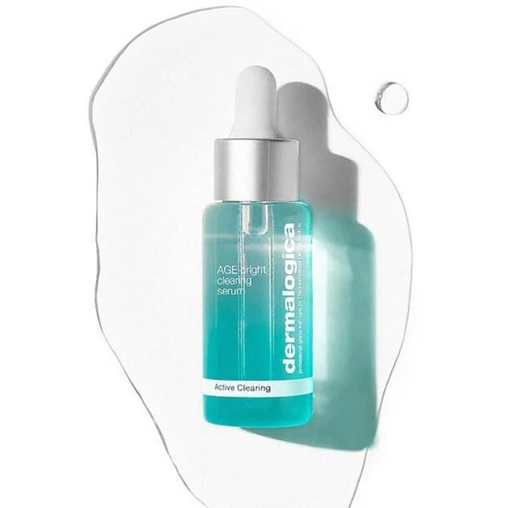Dermalogica AGE Bright Clearing Serum klar flaske med sølvkork liggende i gjennomsiktig flytende tekstur.