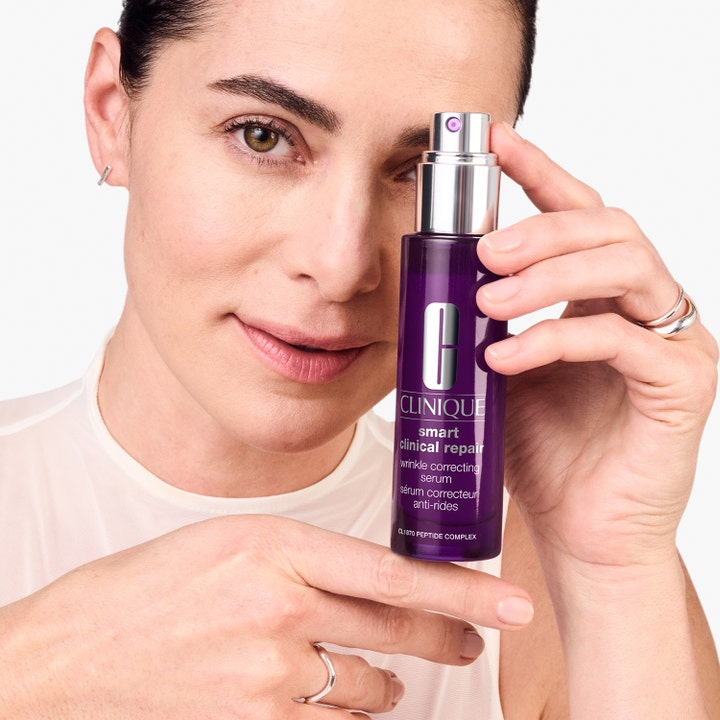 Clinique Smart Clinical Repair 100 ml rynkekorrigerende serum i lilla flaske holdt av en kvinne