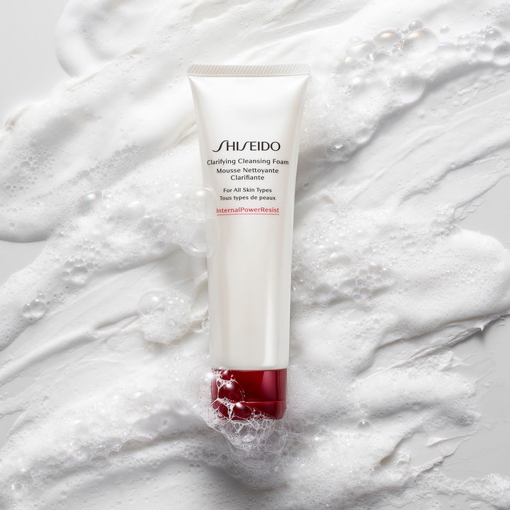 Shiseido Defend Clarifying Cleansing Foam 125 ml ansiktsrens i hvit tube med rød kork omgitt av hvitt skum