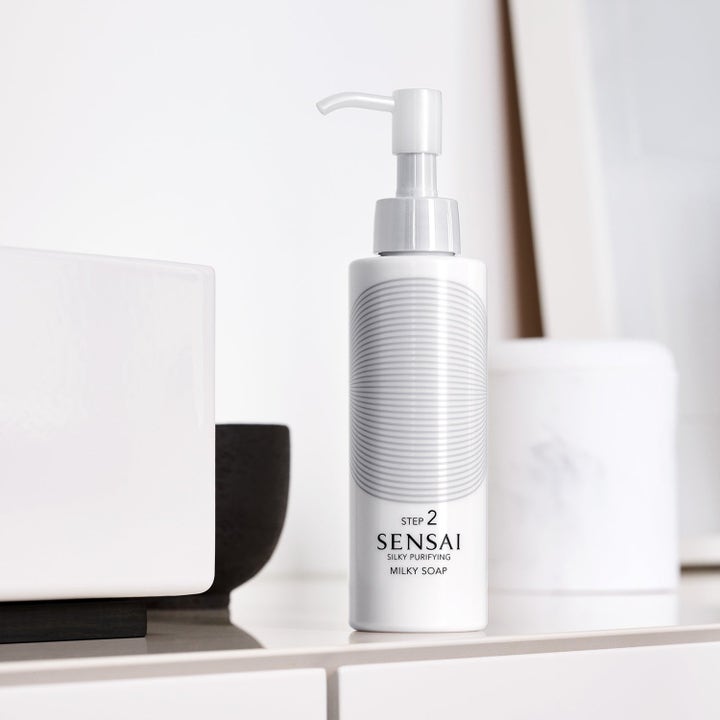 Sensai Silky Purifying Milky Soap ansiktsrens i hvit pumpeflaske med grått sirkelmønster i lyst baderom.