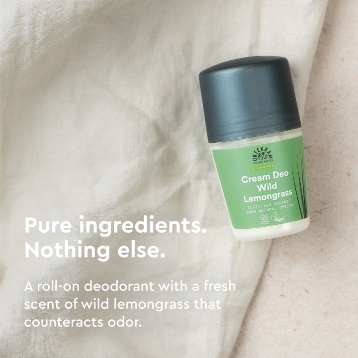 Urtekram Wild Lemongrass Deo 50 ml kremdeodorant motvirker lukt og vises på lyst stoff med tekst om rene ingredienser.