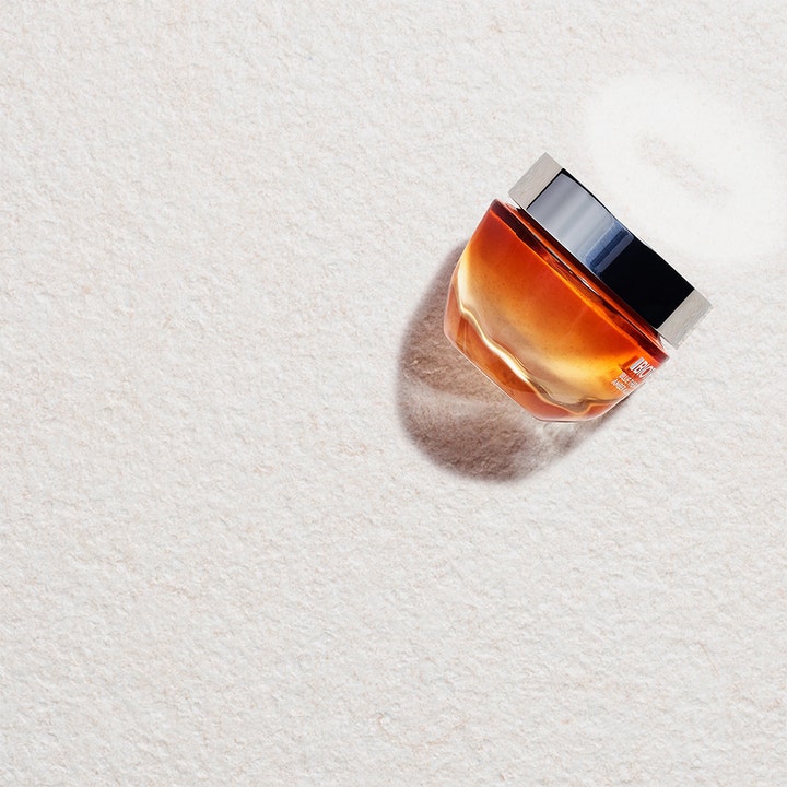 Biotherm Blue Therapy Revitalize 50 ml dagkrem i en oransje glasskrukke som gir glød på lys teksturbakgrunn.