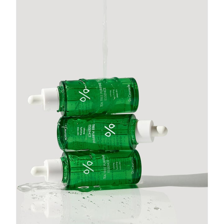 Dr. Ceuracle Tea Tree Purifine Essence 50 ml beroligende essence i grønne glassflasker stablet under rennende vann.