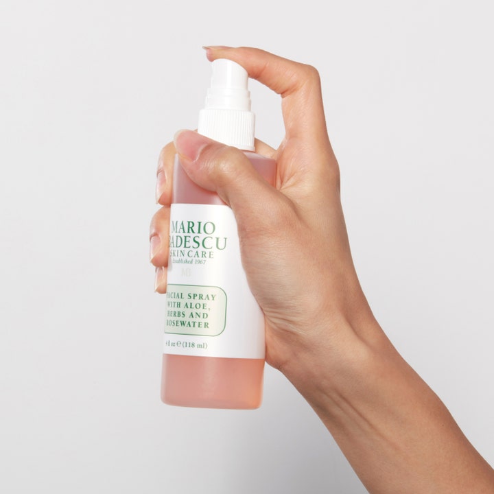 Mario Badescu Facial Spray Aloe, Herbs &amp; Rosewater 118 ml fuktighetsgivende face mist i rosa flaske holdt av en hånd