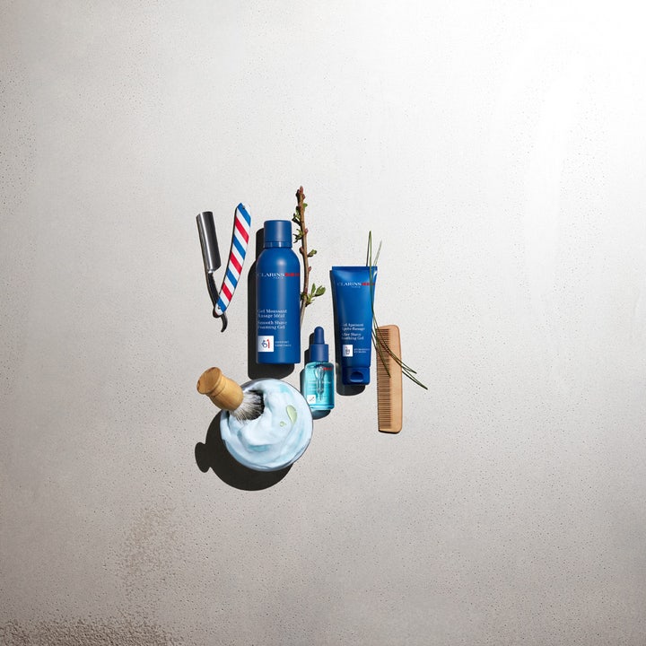 Clarins Men Shave Gel 150 ml rakegelé som gir glatt barbering vist med blå flaske og barberkost i lyseblått skum.