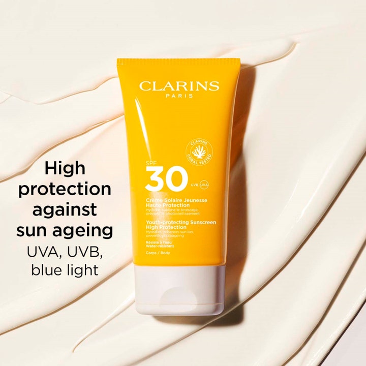 Clarins Youth-protecting Sunscreen SPF30 Body 150 ml beskyttende solkrem i oransje tube på kremet hvit tekstur