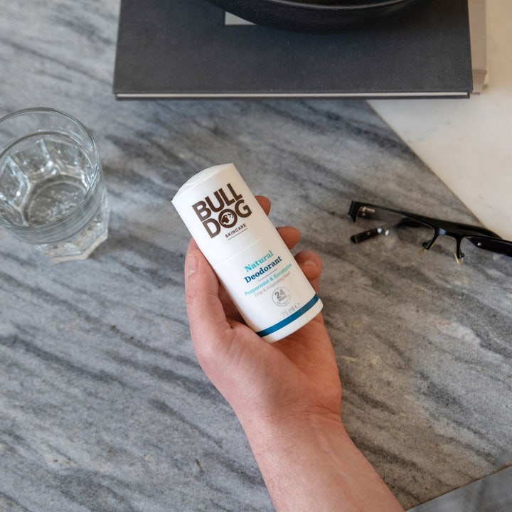Bulldog Peppermint & Eucalyptus 75 ml naturlig deodorant stick i hvit hylse holdes i en hånd over marmor.