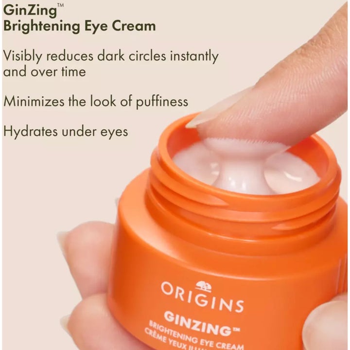 Origins GinZing Brightening Eye Cream i oransje krukke med hvit krem som reduserer mørke ringer.