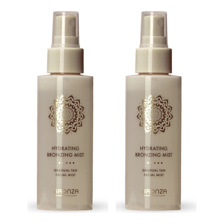 Bronza Hydrating Bronzing Mist duo fuktighetsgivende selvbruning i to klare sprayflasker med hvit kork og gulldetaljer.