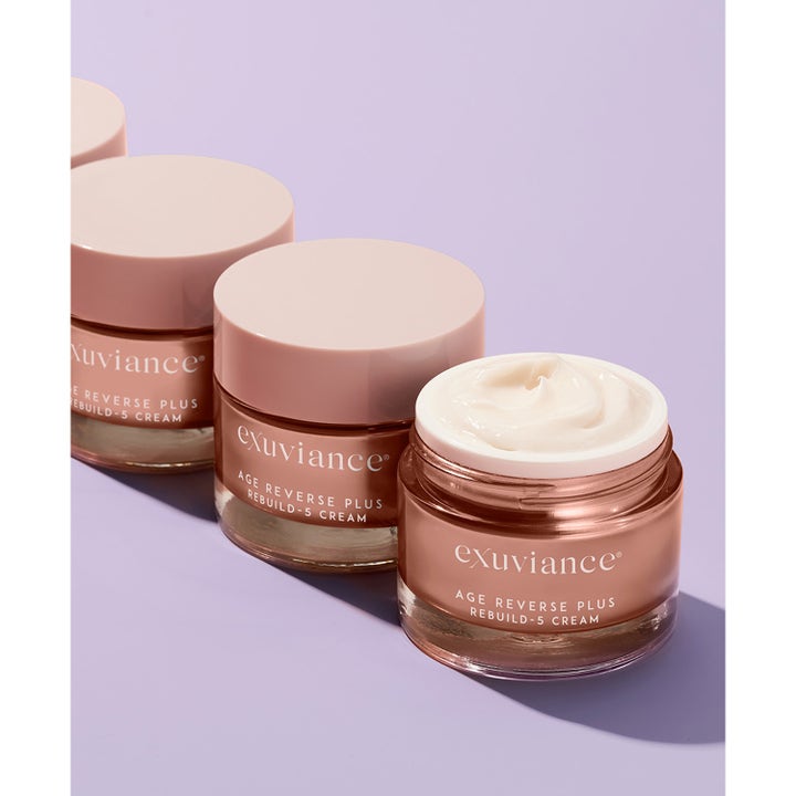 Exuviance Age Reverse + Rebuild-5 Cream 50 ml ansiktskrem i rosegull krukker med fyldig tekstur og lilla bakgrunn.