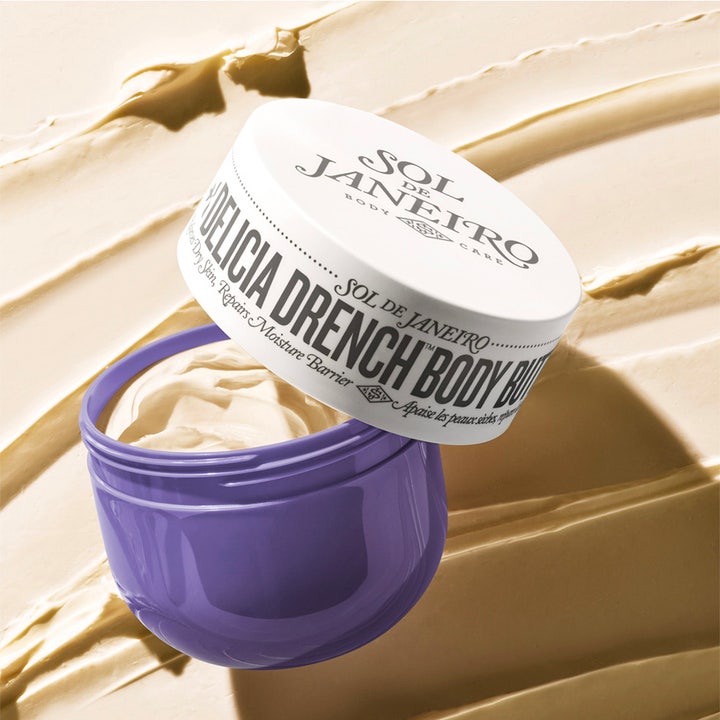 Sol de Janeiro Delicia Drench Body Butter 75 ml fuktighetskrem i lilla krukke med fyldig tekstur i bakgrunnen