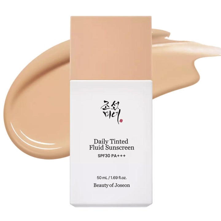 Beauty of Joseon Daily Tinted Fluid Sunscreen 50 ml gir glød i hvit flaske med beige kremtekstur bak.