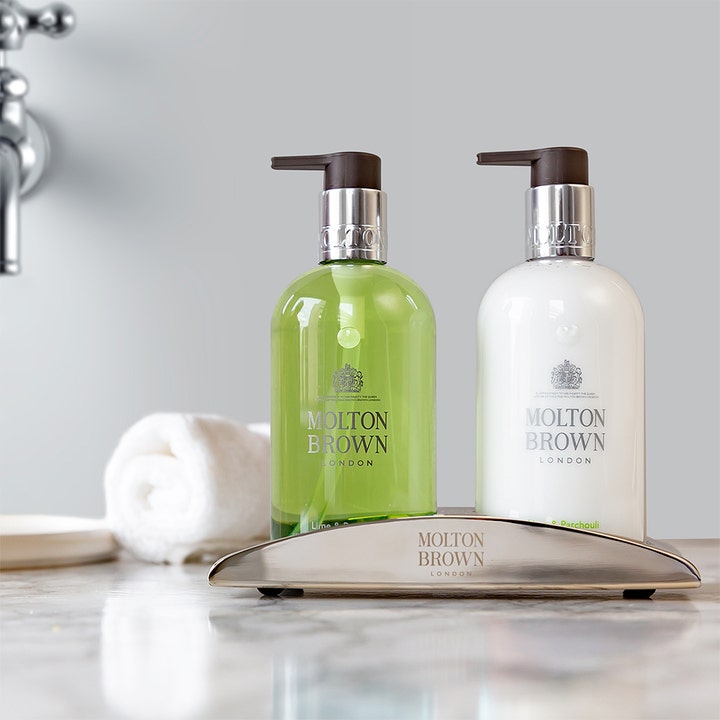 Molton Brown Lime & Patchouli 300 ml handsåpe og lotion i pumpeflasker på et sølvstativ på et bad