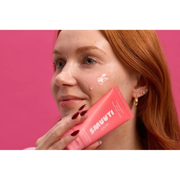 Smuuti Skin Strawberry Boost Wrapping Mask 70 ml i rosa tube påføres som en klar gel på kinnet til en kvinne.