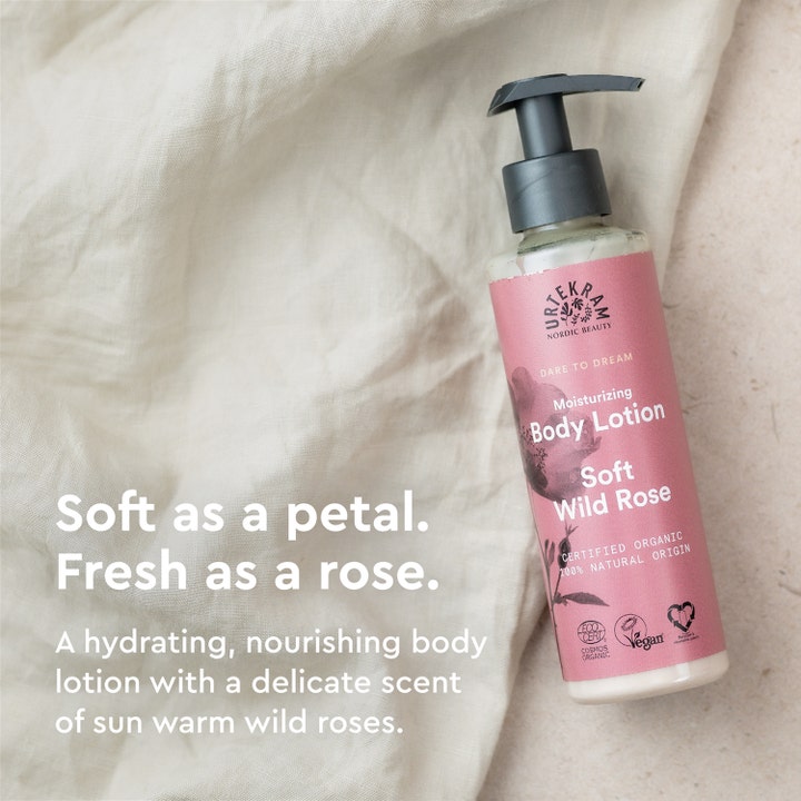 Urtekram Soft Wild Rose 245 ml fuktighetsgivende body lotion i rosa pumpeflaske på lyst tekstil