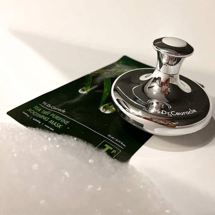 Dr. Ceuracle Cryo Tool 1 stk kjølende hudpleieverktøy i sølv plassert oppå en Tea Tree Purifine ansiktsmaske