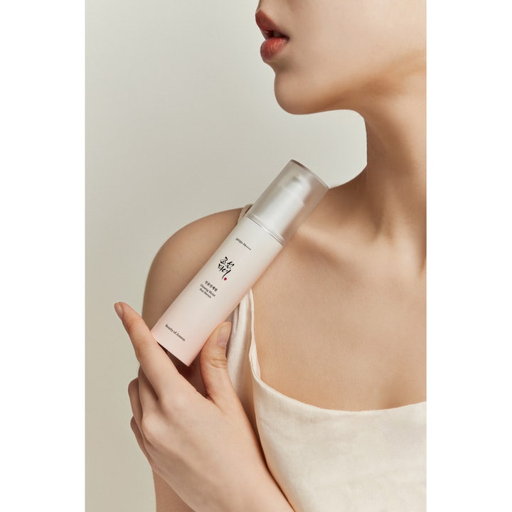 Beauty of Joseon Ginseng Moist Sun Serum 50 ml fuktighetsgivende solserum med SPF 50 i pumpeflaske holdt av en person.