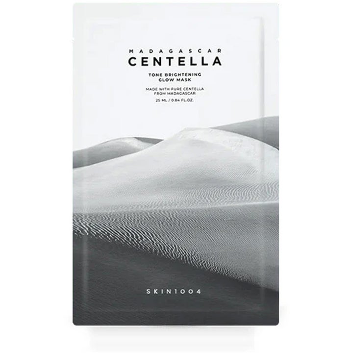 SKIN1004 Madagascar Centella Tone Brightening Glow Mask 25 ml glødgivende ansiktsmaske i hvit pose med grå sanddyner.