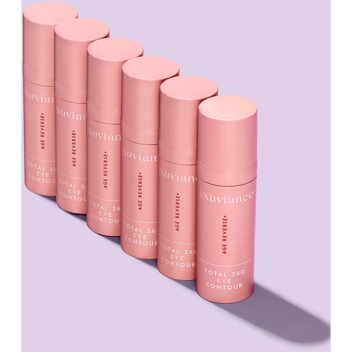 Exuviance Age Reverse Eye Contour 15 g øyekrem mot rynker vist som seks rosa tuber på lilla bakgrunn.