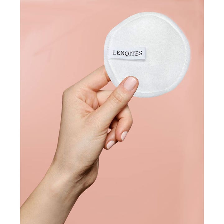 Lenoites Pure Premium Organic Reusable Rounds 5 stk gjenbrukbar hvit pad med logo holdes mot rosa bakgrunn.
