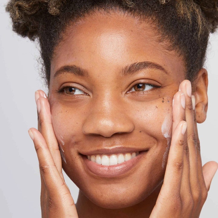 Dermalogica Skin Smoothing Cream 100 ml fuktighetsgivende ansiktskrem påføres av en smilende kvinne på kinnene.