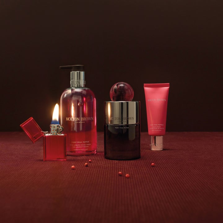 Molton Brown Fiery Pink Pepper 300 ml velduftende håndsåpe ved en tent rød lighter og små pepperkorn