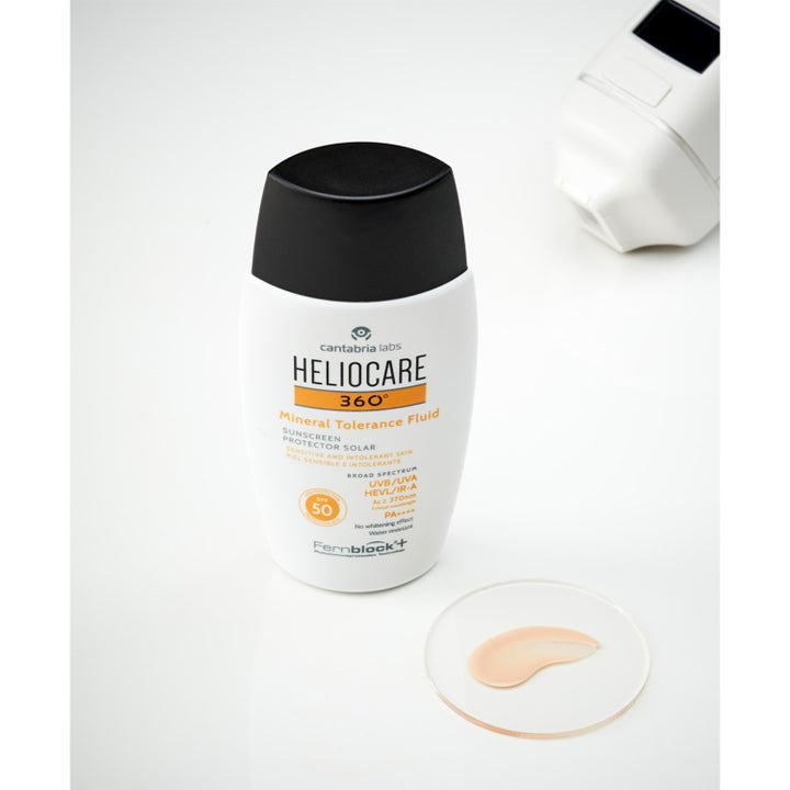 Heliocare Mineral Tolerance Fluid SPF 50 50 ml solkrem med farget tekstur på glassplate ved hvit flaske