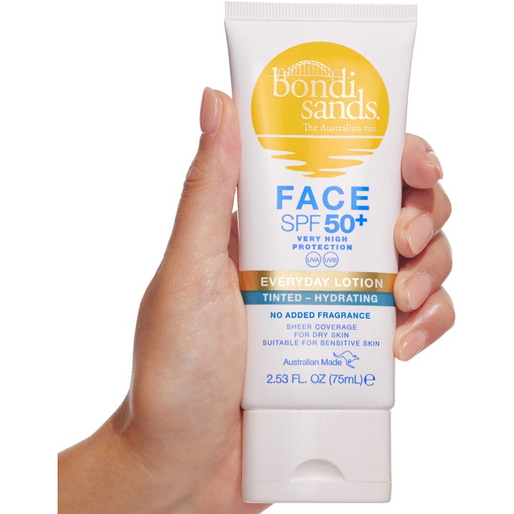 Bondi Sands Spf 50+ Everyday Face Lotion Tinted 75 ml fuktgivende farget solkrem i hvit tube holdt i en hånd