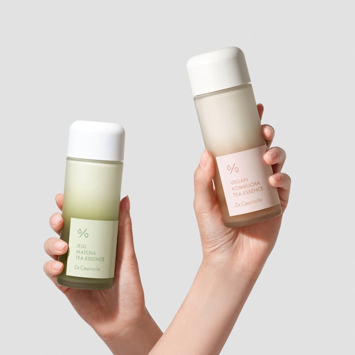 Dr. Ceuracle Jeju Matcha Tea Essence 150 ml toner i frostet glassflaske holdt ved siden av Vegan Kombucha Tea Essence.