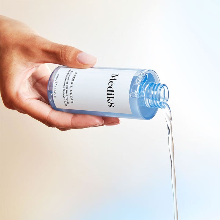 Medik8 Press & Clear 150 ml BHA-toner med salisylsyre helles fra en blå flaske og gir en klarere hud.