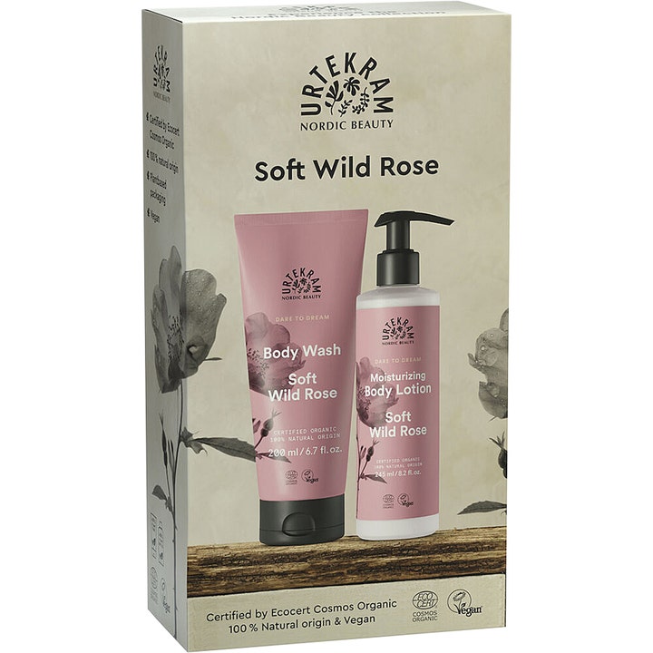 Urtekram Soft Wild Rose gavesett fuktighetsgivende kroppspleie i rosa tube og hvit pumpeflaske i en eske med villroser.
