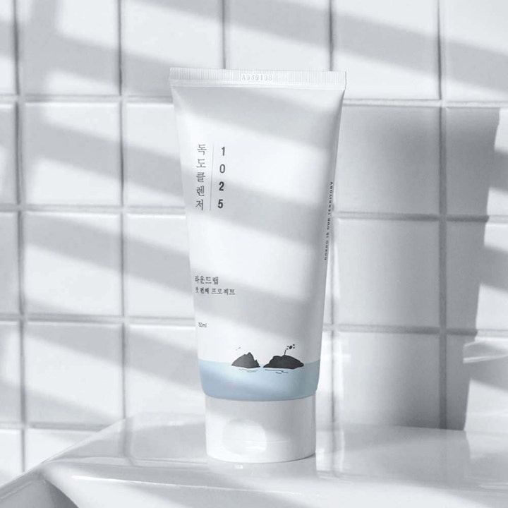 Round Lab 1025 Dokdo Cleanser 150 ml fuktighetsgivende ansiktsrens i hvit tube mot flislagte vegger