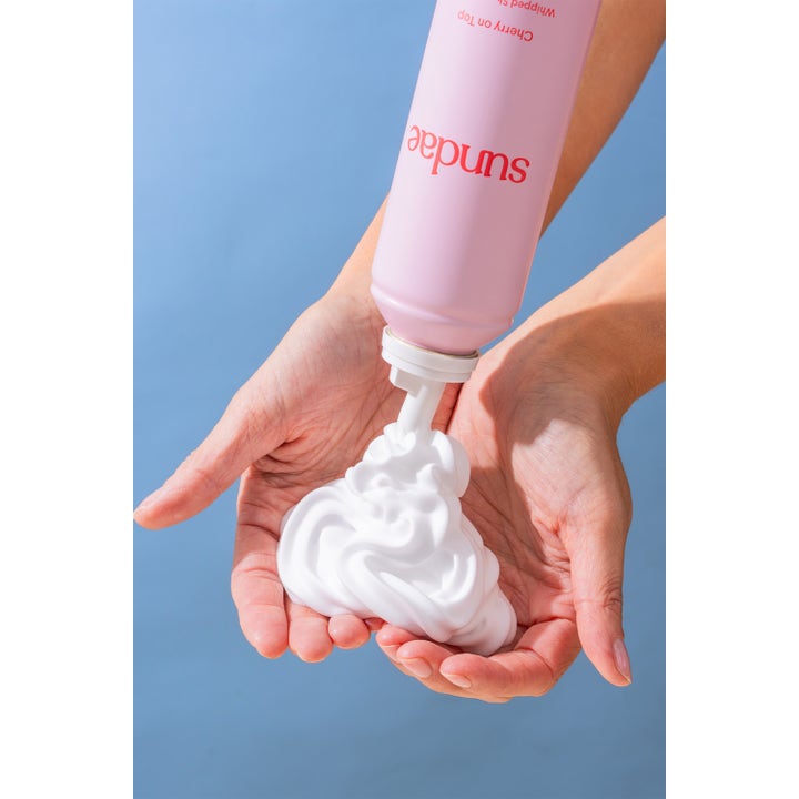 Sundae Whipped Shower Foam Cherry On Top 265 ml dusjsåpe gir fyldig hvitt skum fra en rosa flaske i hendene.