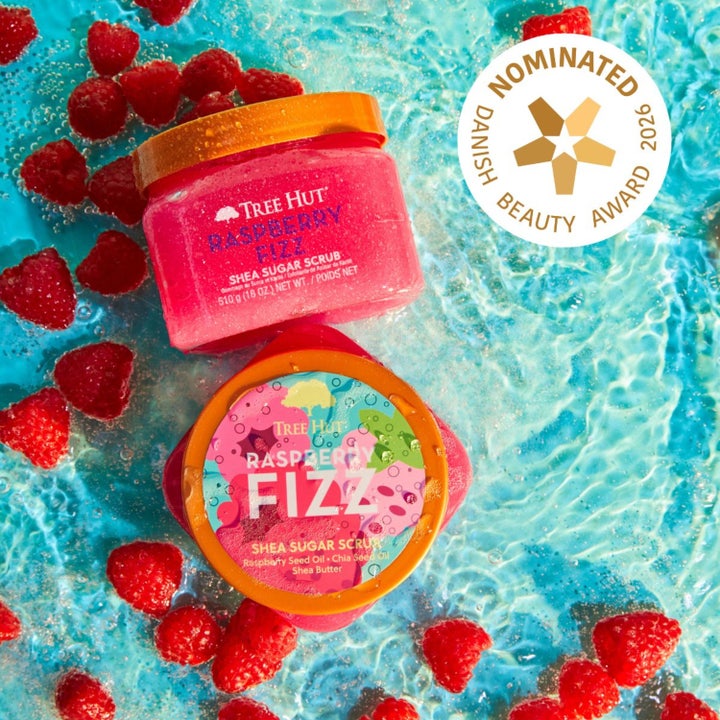 Tree Hut Raspberry Fizz Shea Sugar Scrub 510 g eksfolierende body scrub i rosa krukker omgitt av bringebær i vann.