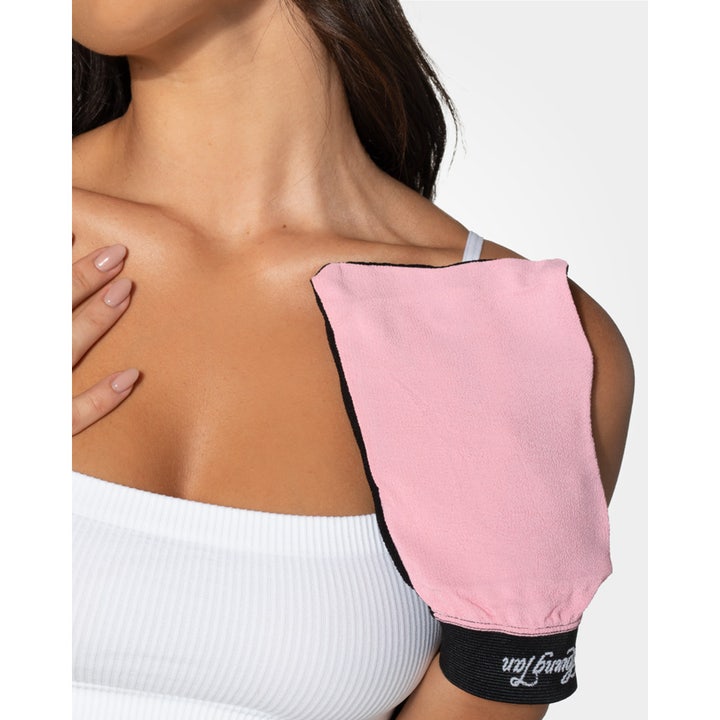 Loving Tan Tan Removing & Skin Polishing Glove 1 stk eksfolieringsvante i rosa og sort på en skulder