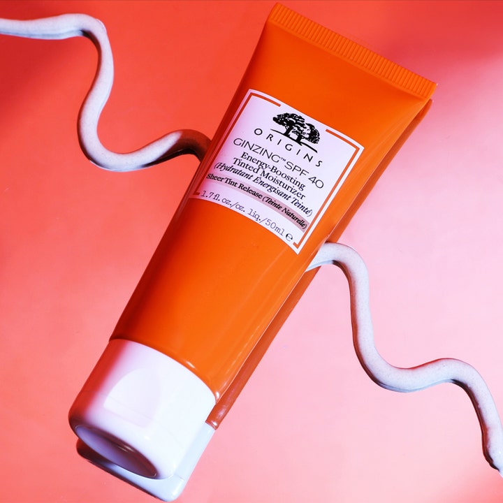 Origins GinZing SPF40 50 ml farget dagkrem på oransje tube med hvit bølge av kremet tekstur.