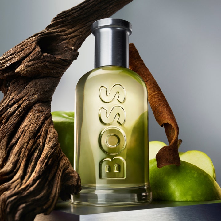 Hugo Boss Boss Bottled 150 ml deospray i glassflaske med preget logo ved friske grønne epler kanelstang og treverk