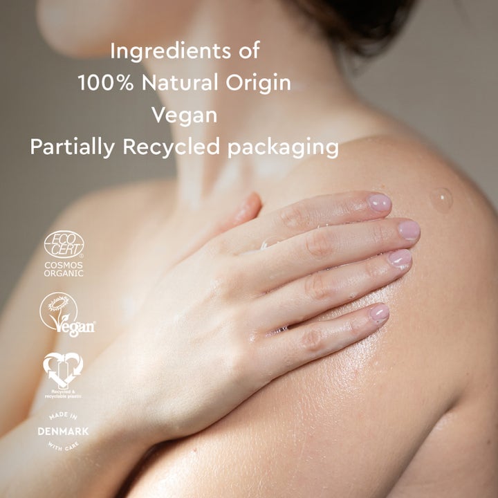 Urtekram Nordic Berry Creamy Body Wash 500 ml vegansk dusjsåpe påført på hud med tekst om 100 % naturlig opprinnelse.