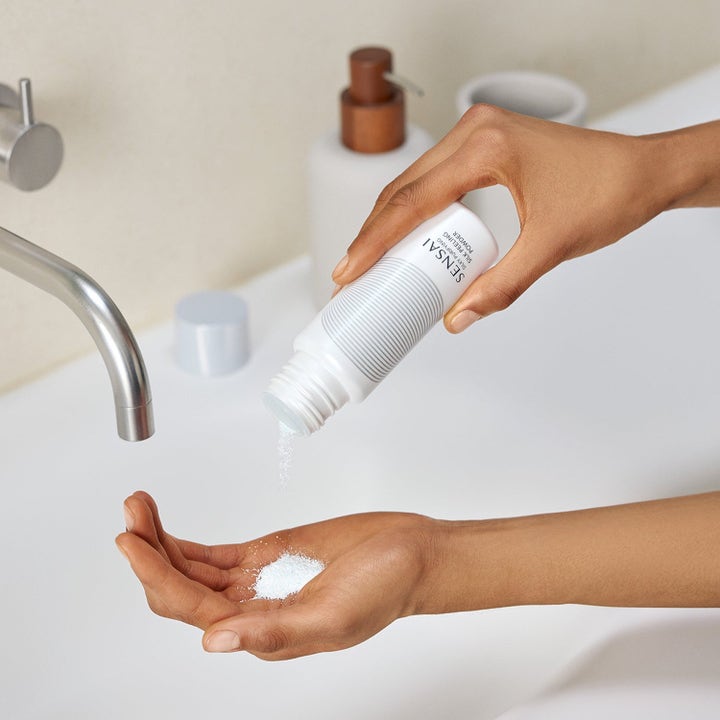 Sensai Silky Purifying Peeling Powder ansiktsskrubb helles i håndflaten for en dyprensende og eksfolierende effekt.
