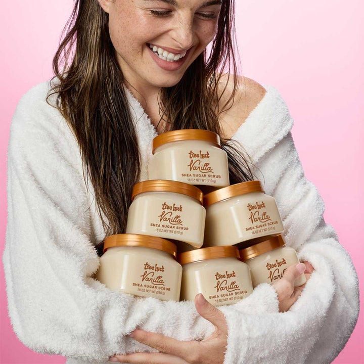 Tree Hut Shea Sugar Scrub Vanilla 510 g kropspeeling holdes av smilende kvinne i hvit morgenkåpe