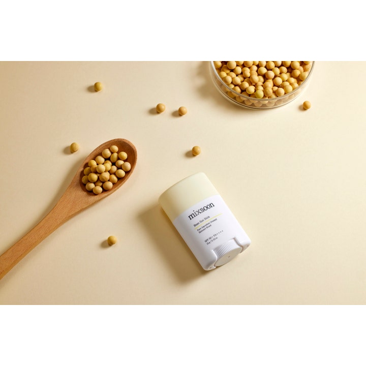 Mixsoon Bean Sun Stick 15 g solstift for ansiktet ved siden av en treskje fylt med soyabønner