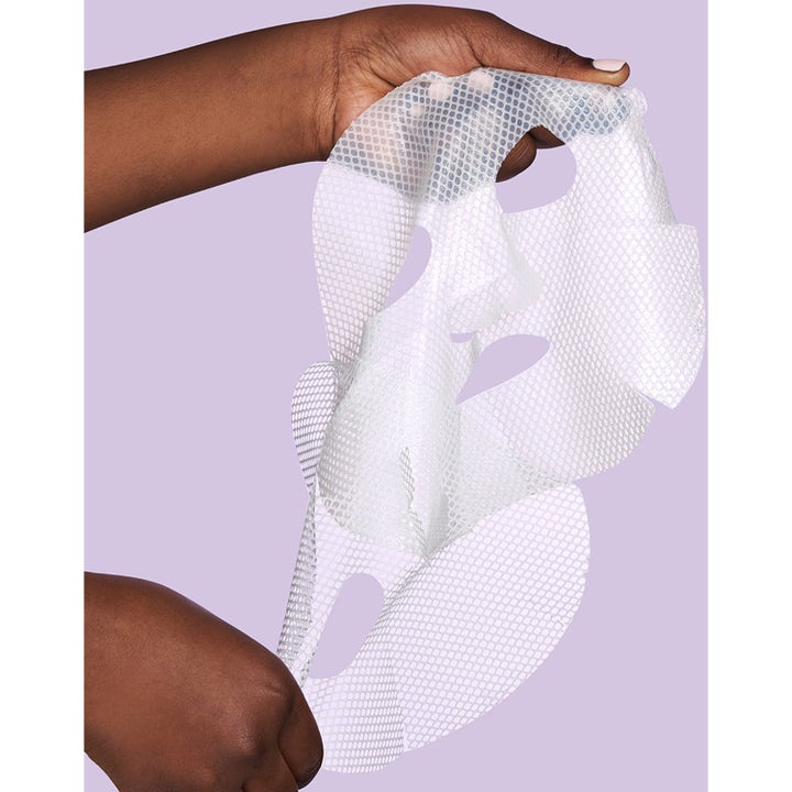 Exuviance Pick-Me-Up Plumping Mask 20 g fuktighetsgivende sheet mask i hvit mesh holdt mot lilla bakgrunn