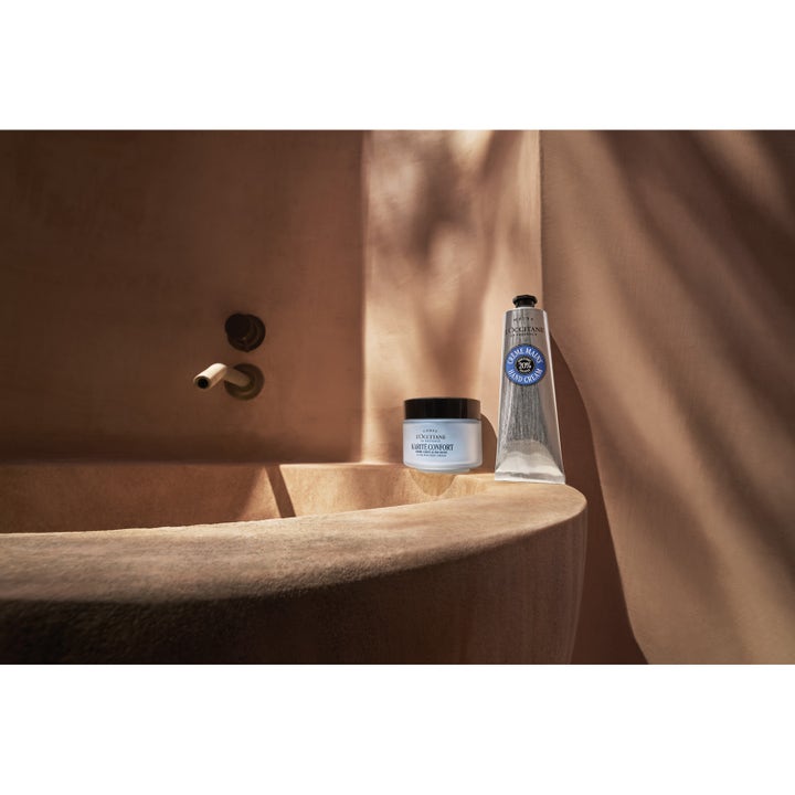L'Occitane en Provence Shea Butter Ultra Rich Body Cream 200 ml pleiende kroppskrem i glasskrukke ved et badekar.