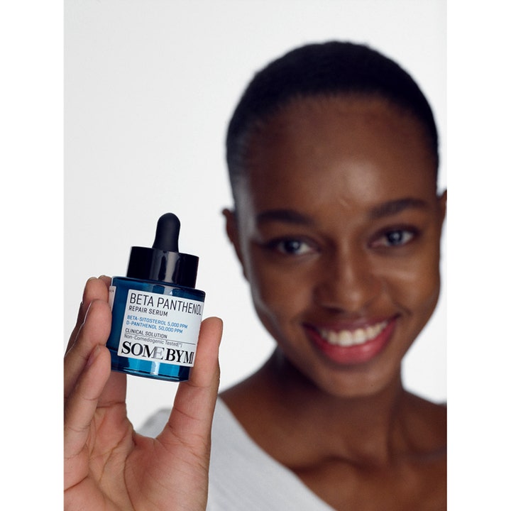 Some By Mi Beta Panthenol Repair Serum 30 ml holdes av en smilende kvinne for å vise den blå glassflasken.