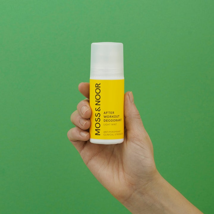 Moss & Noor After Workout Deodorant Light Mint 60 ml antiperspirant i gul roll-on som holdes i en hånd mot grønn bakgrunn