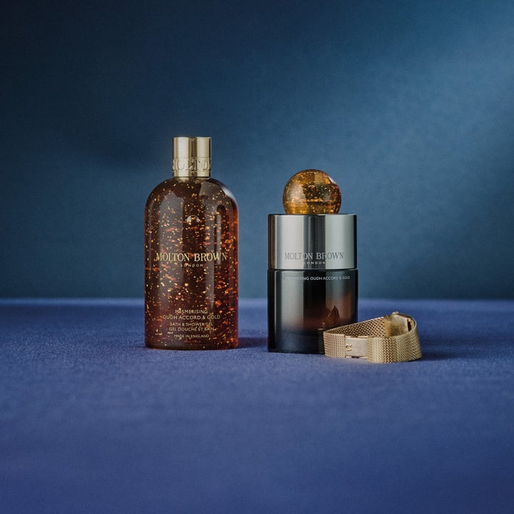 Molton Brown Mesmerising Oudh Accord & Gold 300 ml dusjgelé med gullflak ved siden av en matchende parfyme.
